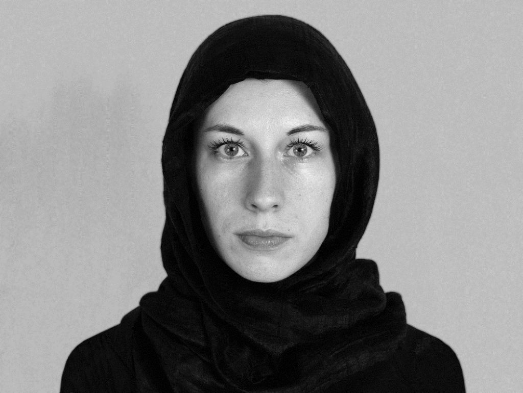 Raksta autore Zane Balčus 2003. gadā, hidžabā fotografējoties pasei, ar kuru ieceļot Irānā. Fotogrāfija no grāmatas "Arsenāls. Kādas ķecerības vēsture".